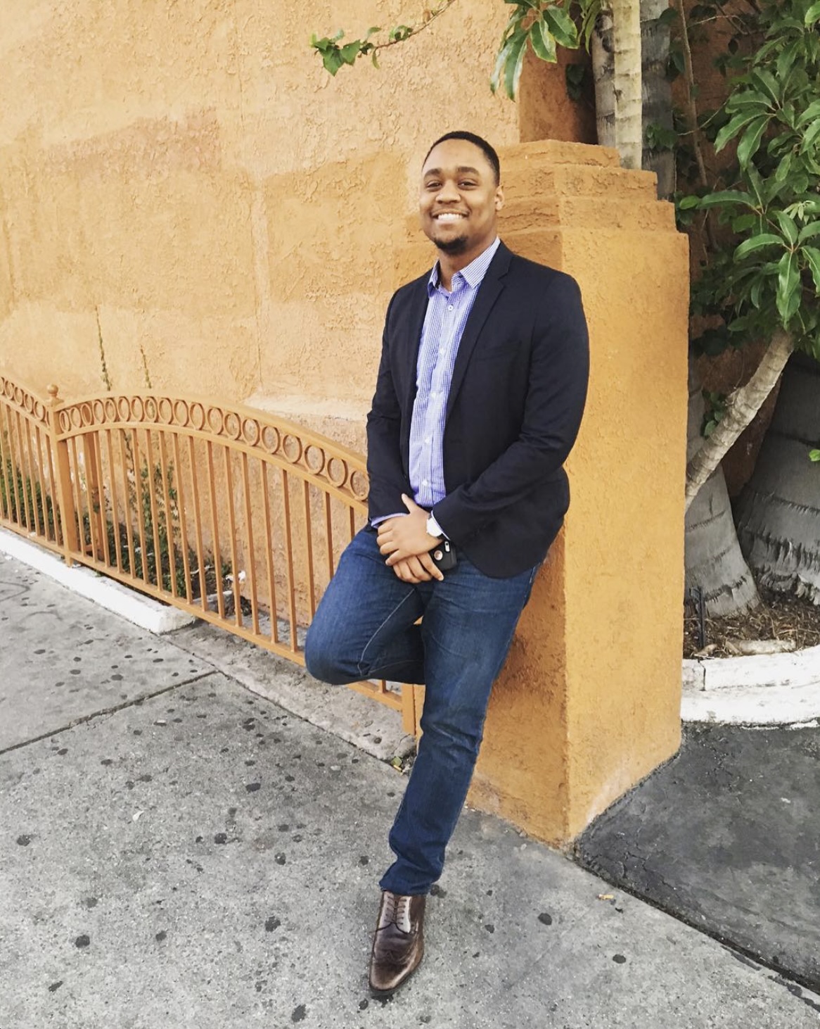 Jarrett, founder of The Civic Brief, smiling in a navy blazer while leaning against an ochre stucco wall